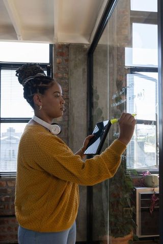 African American Woman Writing on Glass Board in Contemporary Office