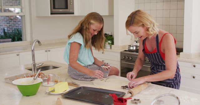 Image shows Caucasian mother and daughter smiling and making star shaped cookies together in the kitchen. Perfect for depicting family bonds, mom and child activities, homemade baking, domestic happiness, parenting tips, and culinary holiday themes. Useful for family-oriented blogs, lifestyle websites, parenting magazines, and baking advertisements.