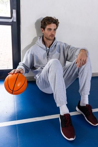 Man Sitting on Indoor Court Holding Basketball