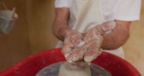Senior artisan cleansing hands in ceramic studio