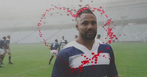 Rugby player standing on foggy stadium pitch wearing navy white jersey with heart overlay