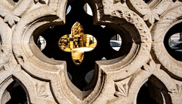 Quatrefoil stone lattice framing urban street with yellow taxi and motion blur