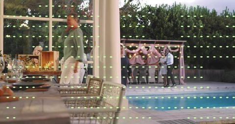 Evening backyard gathering by pool with pergola dining, string lights and relaxed mingling