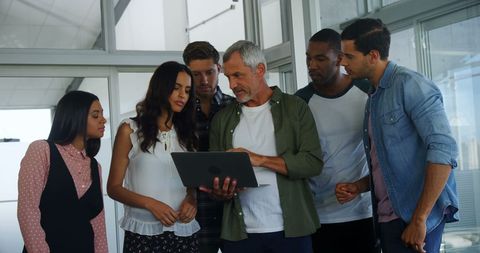 Diverse professionals collaborating over a laptop in office
