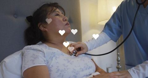 Nurse listening to heartbeat at bedside, patient receiving compassionate home care with heart icons
