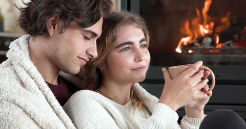 Cozy Couple Relaxing by the Fireplace with Warm Drink