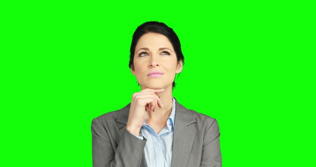 A Caucasian businesswoman appears contemplative, with copy space on the green background for text. Her thoughtful expression suggests she's pondering a decision or idea in a professional context.