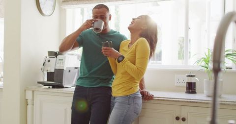 Happy Couple Enjoying Coffee and Laughter in Bright Kitchen