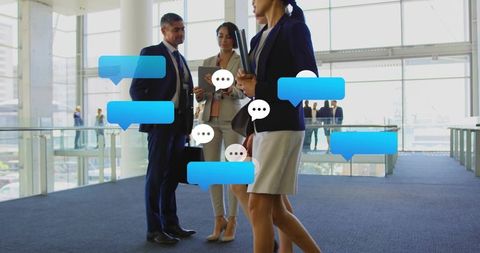 Business professionals collaborating with digital chat bubbles over tablet in modern atrium