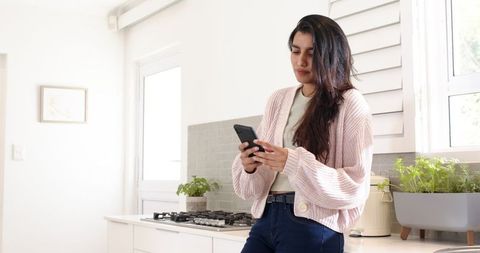 Young woman using smartphone in modern kitchen