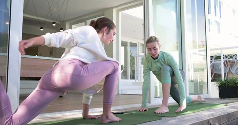 Sunlit partner yoga on deck with smartphone workout guide for morning stretch and wellness