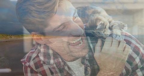 Laughing man holding kitten on shoulder blending with coastal beach double exposure