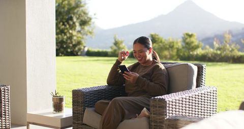 Woman Relaxing Outdoors with Smartphone Amid Scenic Landscape