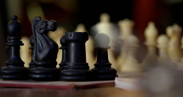 A close-up view of a chessboard with focus on the black knight and other chess pieces in the background, with copy space. Chess is a strategic board game that requires foresight and planning, often symbolizing complex decision-making.
