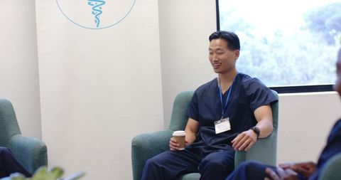 Healthcare team relaxing in clinic lounge holding coffee and wearing visible id badges