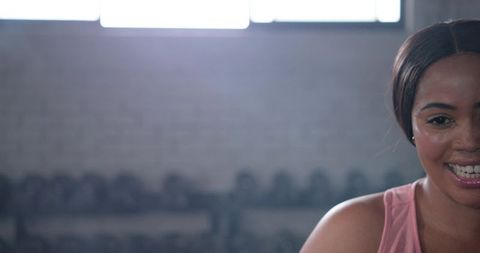 Smiling african american woman pausing after workout in gym with dumbbells and sweat