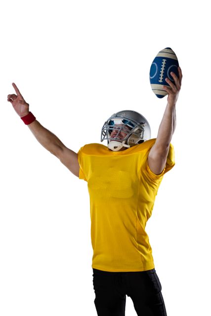 American football player holding ball while standing with arms outstretched against white background