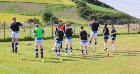 Soccer players drilling with agility ladder on grass field