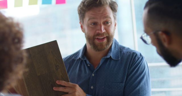 Male Architect Presenting Wood Flooring Options to Colleagues - Download Free Stock Images Pikwizard.com