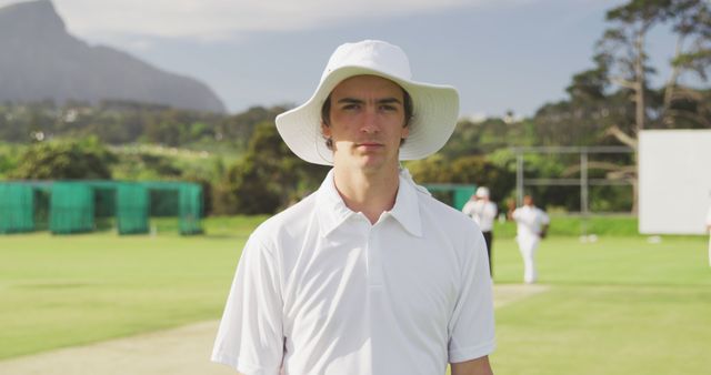 Portrait of caucasian male cricket player wearing hat on field. Cricket, sports, match and active lifestyle, unaltered.