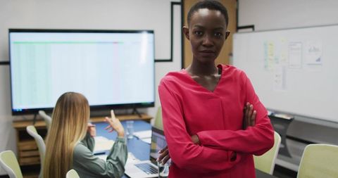 Confident project leader standing with arms crossed in modern office during data review