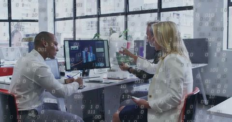 Team analyzing digital data visualizations with binary code overlay in modern open office