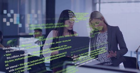 Women Software Developers Collaborating Over Laptop With Code Reflection on Glass Partition