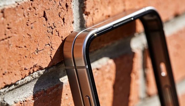 Close-up bronze smartphone frames leaning on red brick wall with strong sunlight shadow