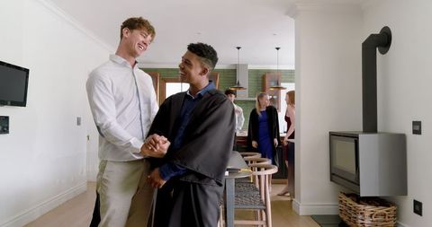 Celebrating graduation at home kitchen party, couple holding hands and smiling