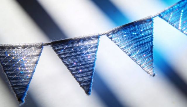 Close-up blue glitter pennant bunting hanging on twine with metallic stitch texture