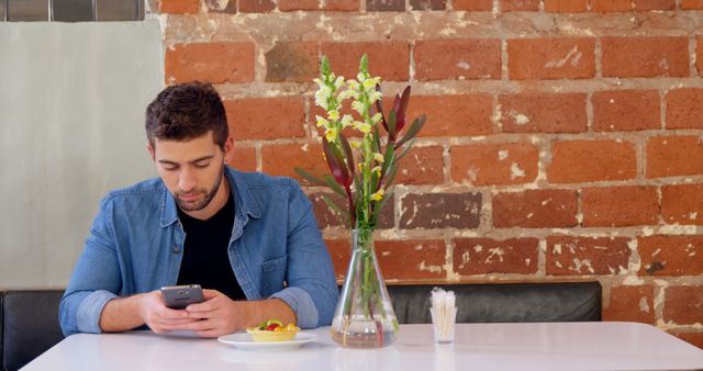 Man Using Smartphone at Cafe Table with Flower Vase - Download Free Stock Images Pikwizard.com