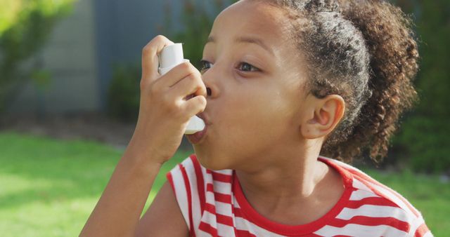 African american girl using asthma inhaler outside in sunny garden. Childhood, illness, summer, health and nature.
