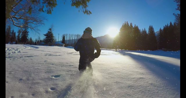 Person running through a snowy field during sunset, creating dynamic snowfall around them. Can be used for promoting winter sports, outdoor activities, or seasonal content. Highlights themes of adventure, nature, and fitness in cold weather.
