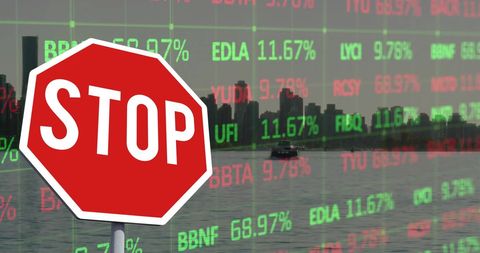 Stop Sign and Stock Market Data Superimposed Over City Skyline