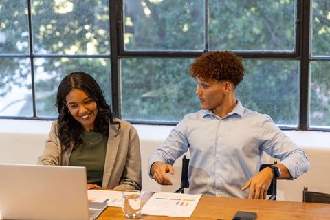 Diverse young professionals collaborating on presentation in modern corporate workspace