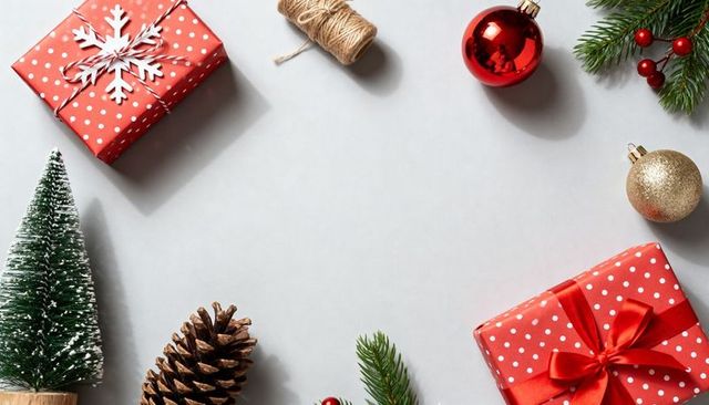 Red polka dot gift box featuring satin ribbon and festive ornaments on pale gray flatlay