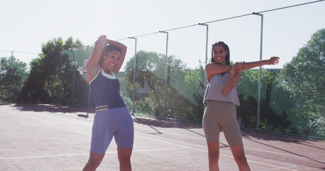 Two Women Stretching on Outdoor Tennis Court on a Sunny Day - Download Free Stock Images Pikwizard.com