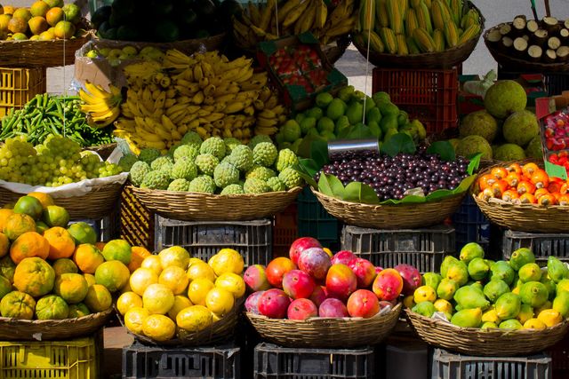 Showcasing an assortment of ripe and vibrant fruits at a farmers market, this image highlights a wide variety of tropical and organic produce. Perfect for use in advertising healthy eating, promoting organic food, or illustrating local agriculture.