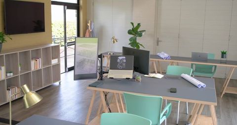 Modern coworking studio featuring desk with laptop schematics and rolled blueprints