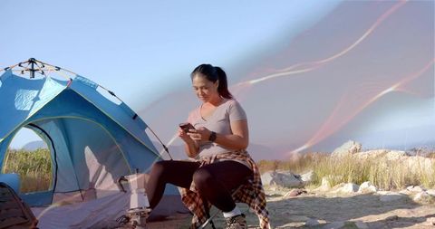 Woman in nature using smartphone at rural campsite