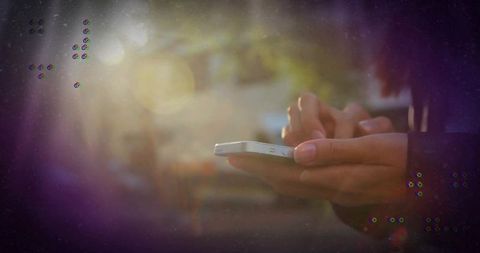 Person Using Smartphone on Sunlit Street