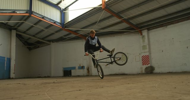 Young BMX Rider Performing Stunt in Abandoned Warehouse - Download Free Stock Images Pikwizard.com