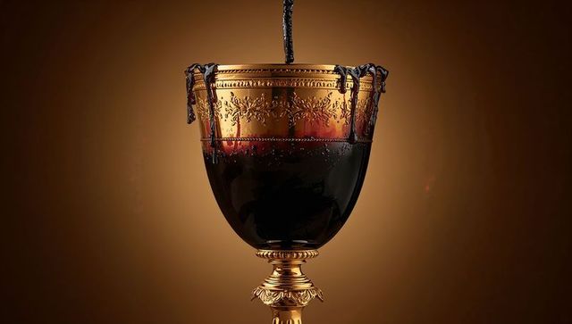 Pouring dark syrup into ornate gilded chalice catching viscous liquid on decorative stem