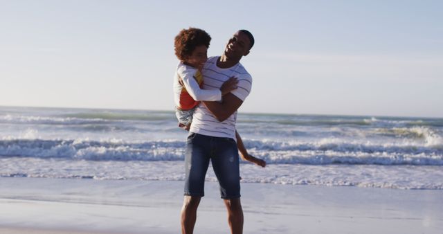 African american father picking up his son and playing at the beach. family travel vacation leisure concept