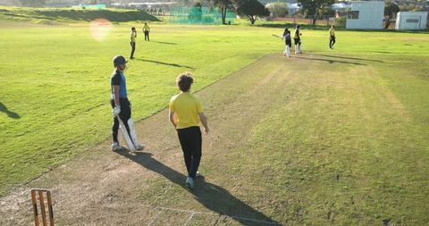 Cricketers practicing on sunny day at local sports ground