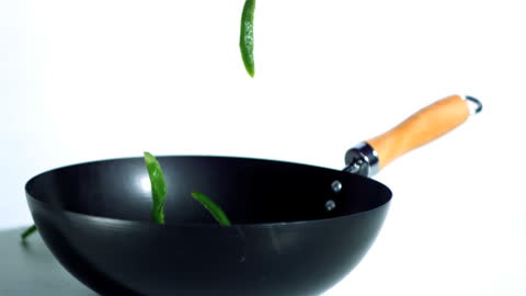 Sliced Green Peppers Falling Into Wok in Slow Motion