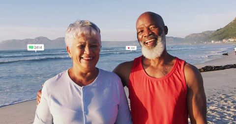 Smiling mature couple enjoying golden hour beach walk with social icons and dog