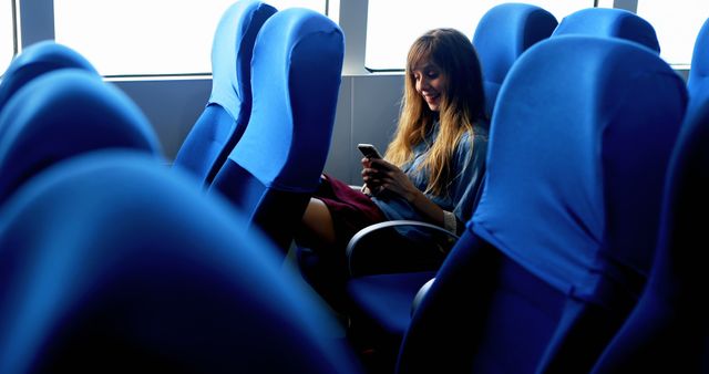 Woman Using Smartphone on Public Transport with Blue Seats - Download Free Stock Images Pikwizard.com