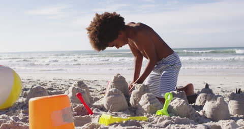 Boy joyfully building sandcastles at sunny beach