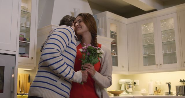 Couple Embracing in Cozy Home Kitchen, Woman Holding Flowers - Download Free Stock Images Pikwizard.com